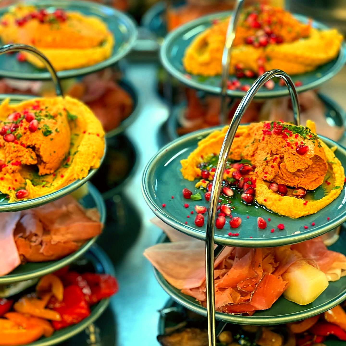Etageren mit bunten Vorspeisen – Hummus, Schinken und Antipasti beim Catering-Buffet
