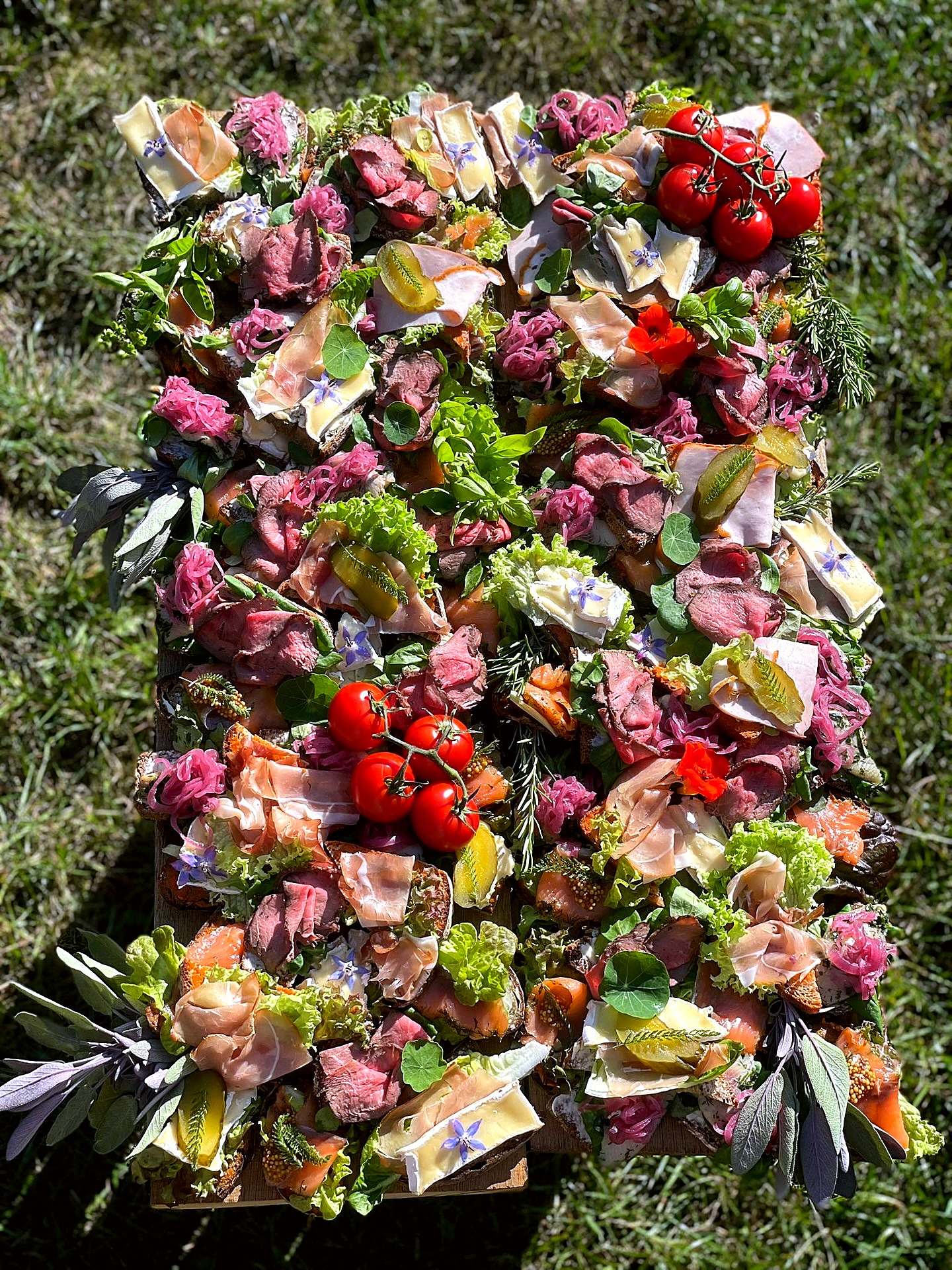 Buntes Fingerfood auf Holzbrett – belegte Brote mit Roastbeef, Lachs und Kräutern vom Catering Fritzi
