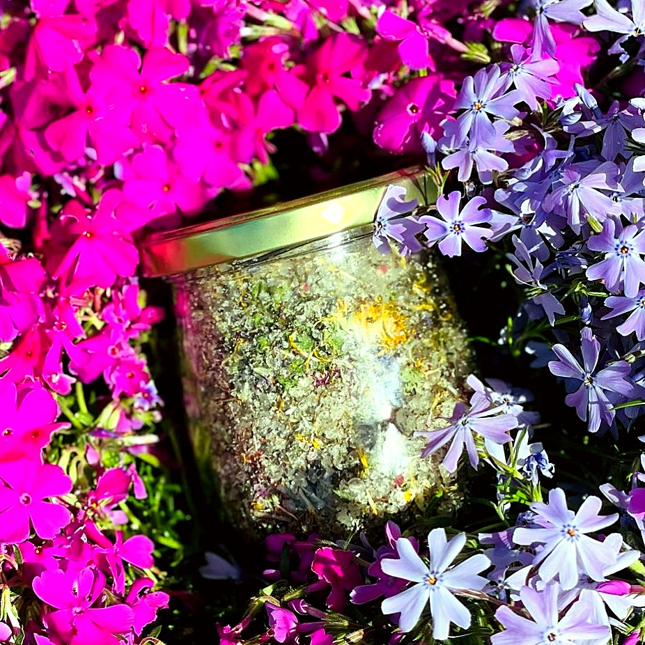 Glas mit Blütenmischung zwischen pink blühendem Phlox – natürliche Zutaten aus dem Garten