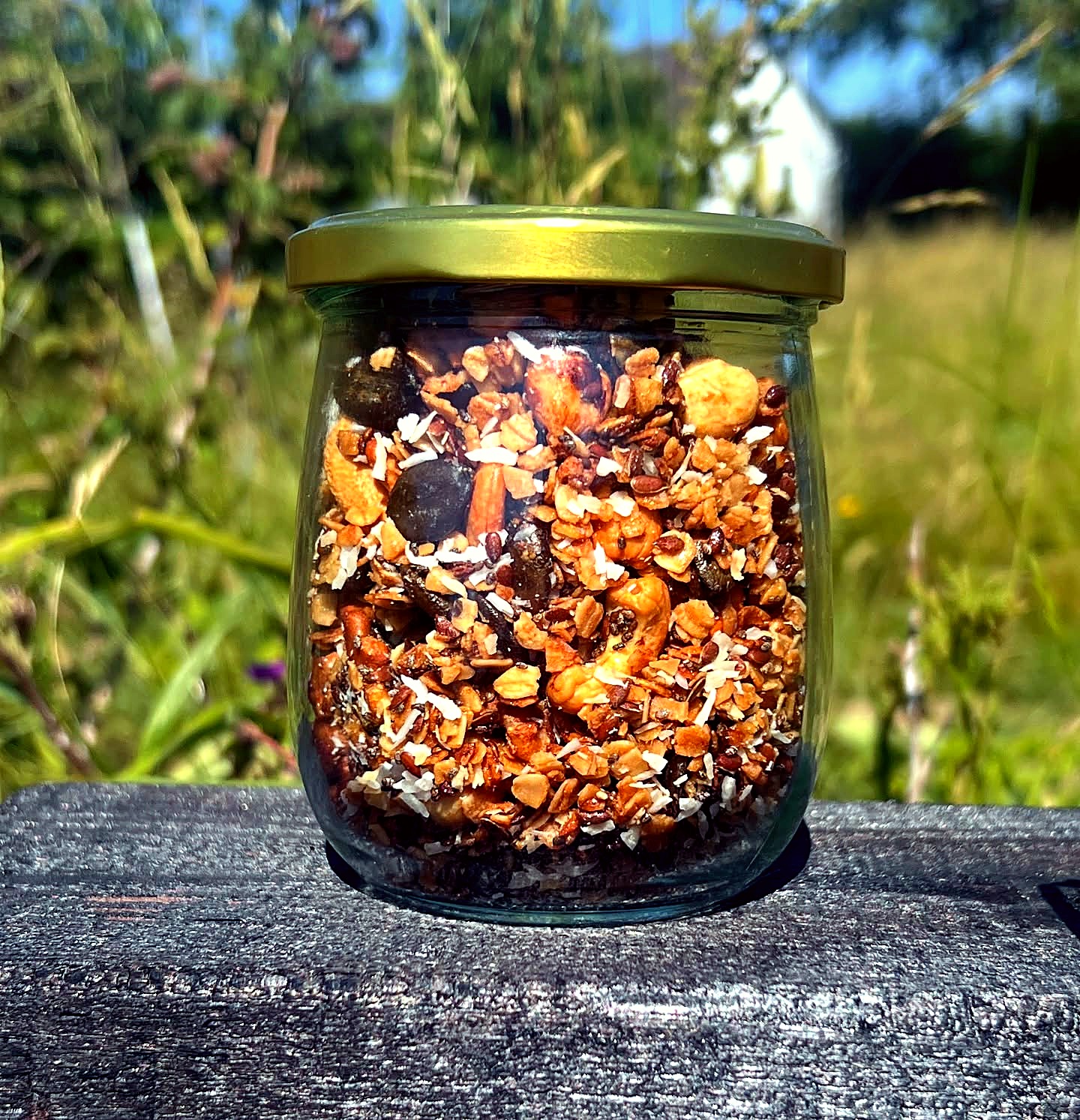 Glas mit hausgemachtem Granola vor sommerlicher Wiese – natürliche Küche vom Privatkoch